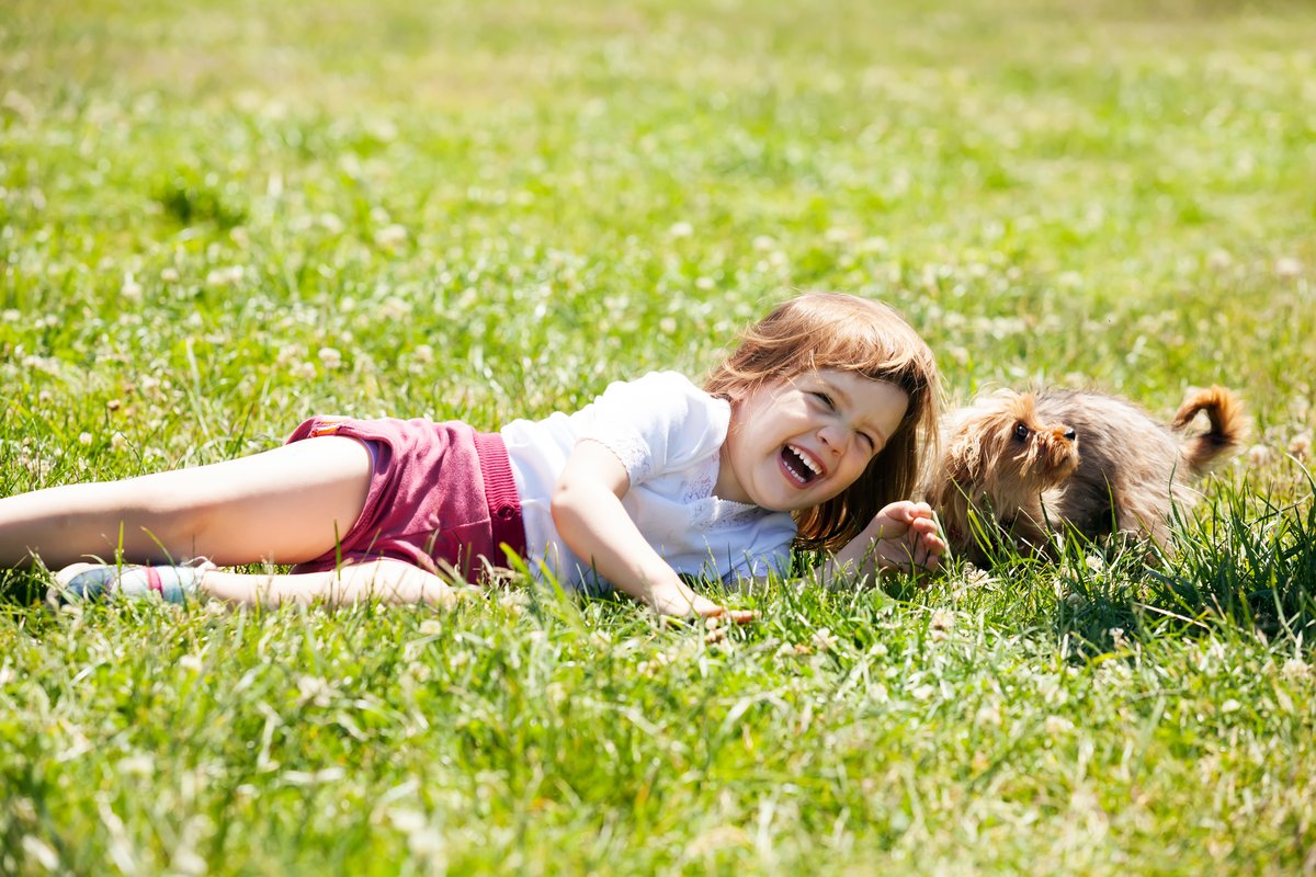 A child and dog relaxing in a yard